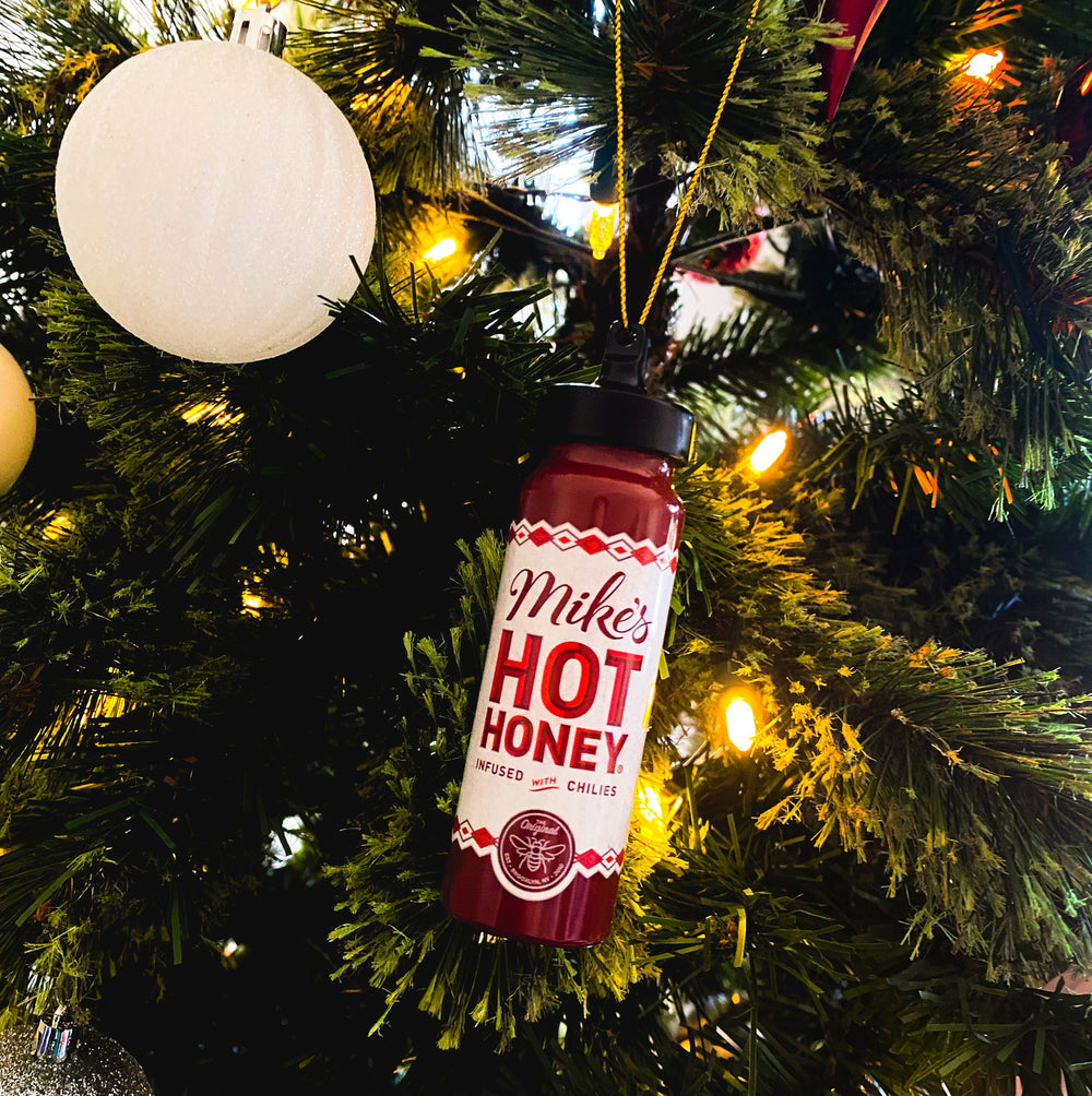 Mike's Hot Honey bottle ornament hanging on a lit tree